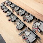 Boss Step-Up Power Modules on their black powder-coated mounting brackets, laid out on a timber workbench