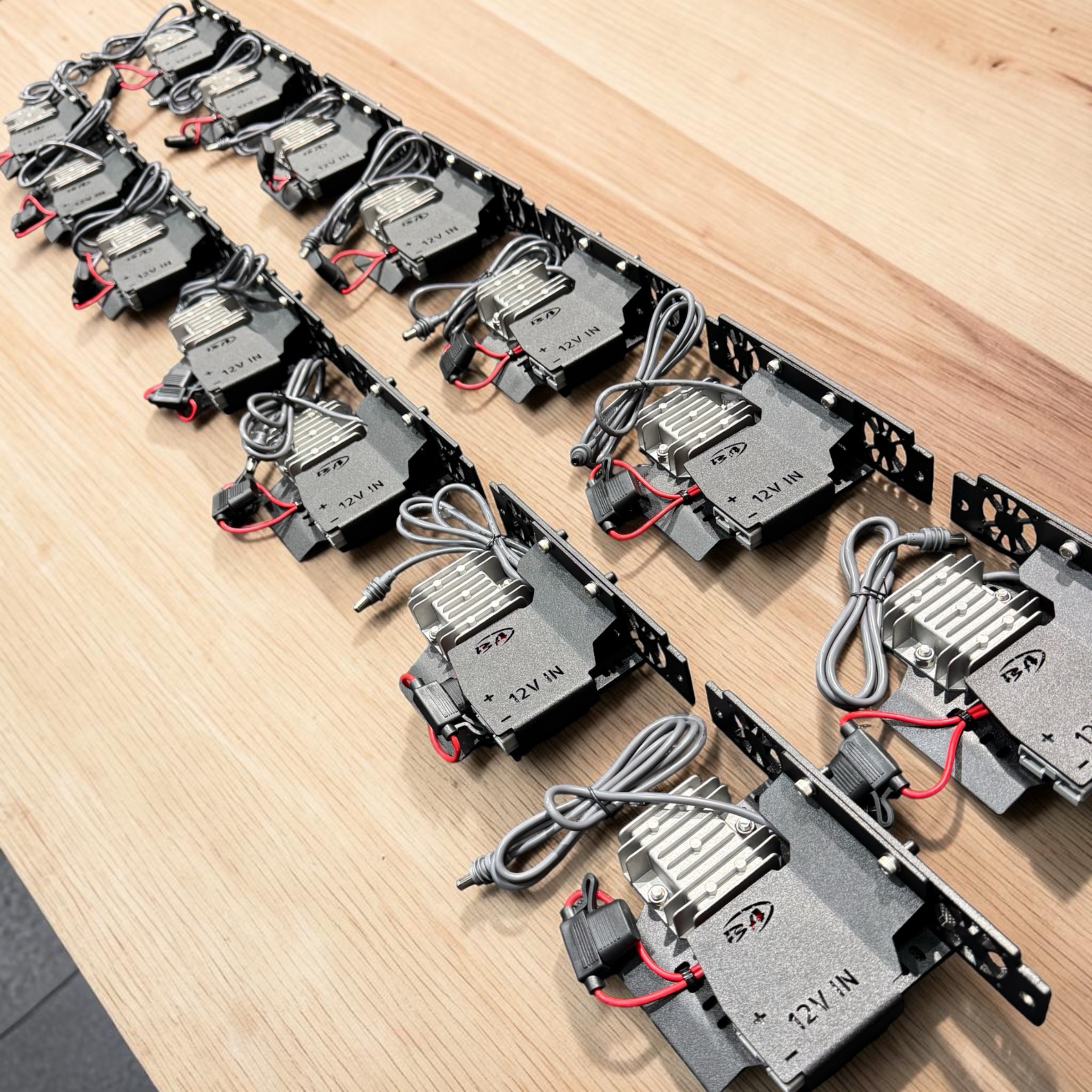 Boss Step-Up Power Modules on their black powder-coated mounting brackets, laid out on a timber workbench