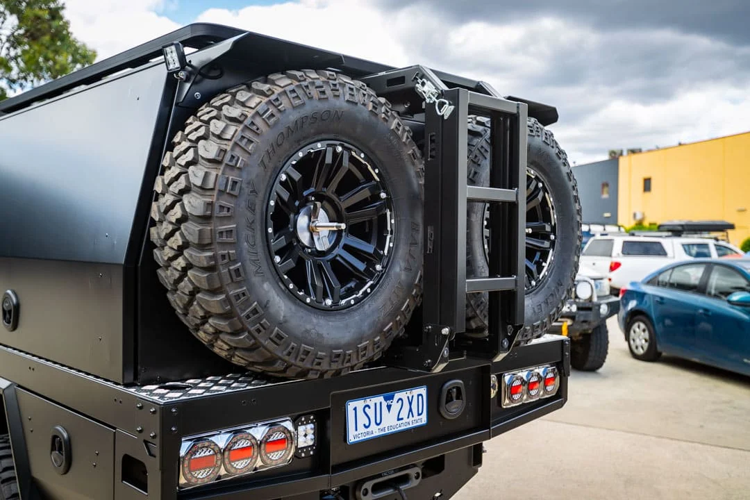 Rear of a Boss M1 canopy on a Toyota HiLux, with spare-wheel mount and ladder